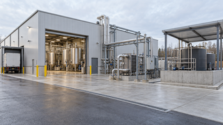 AI-generated illustration of a hypothetical fermentation building with loading access, process vessels and outdoor utility equipment.